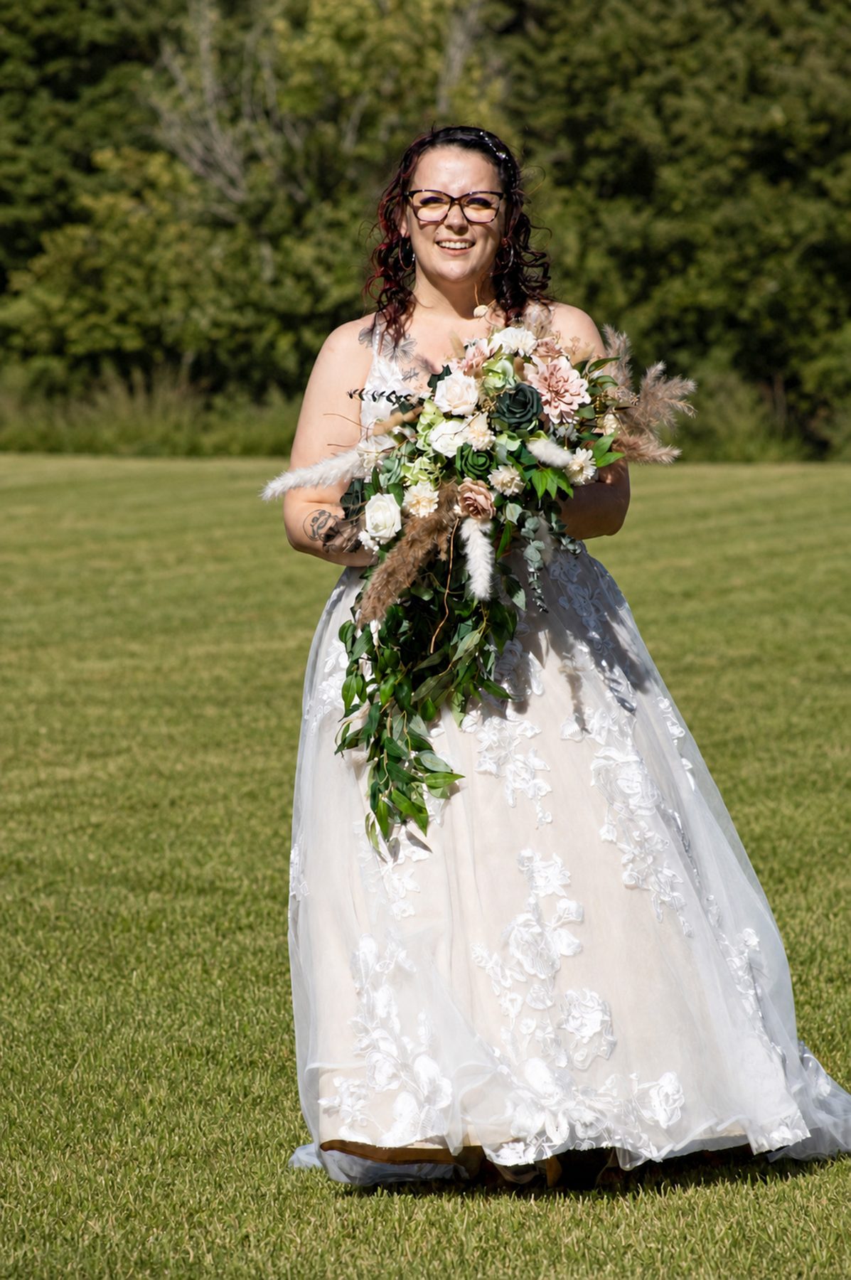 Bride standing in an open field holding her bouquet