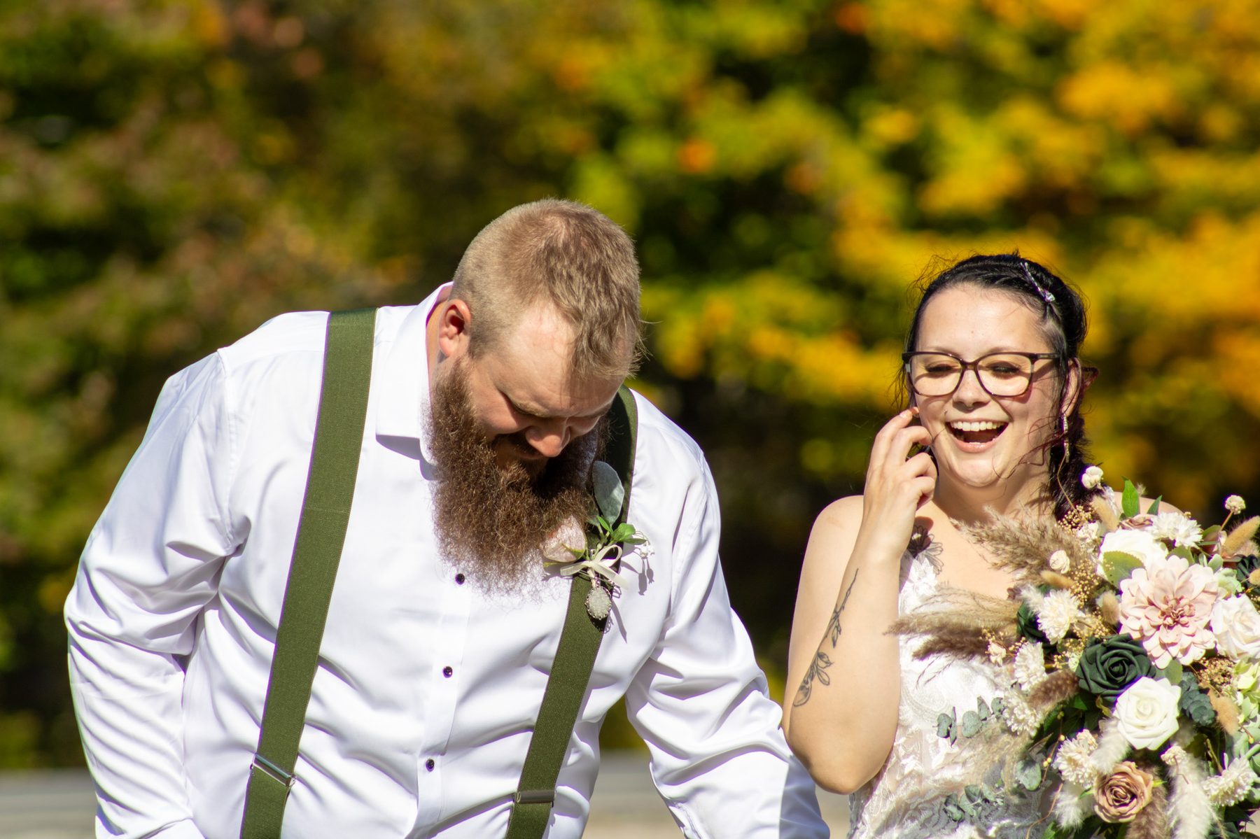 Bride and groom laughing together in autumn light
